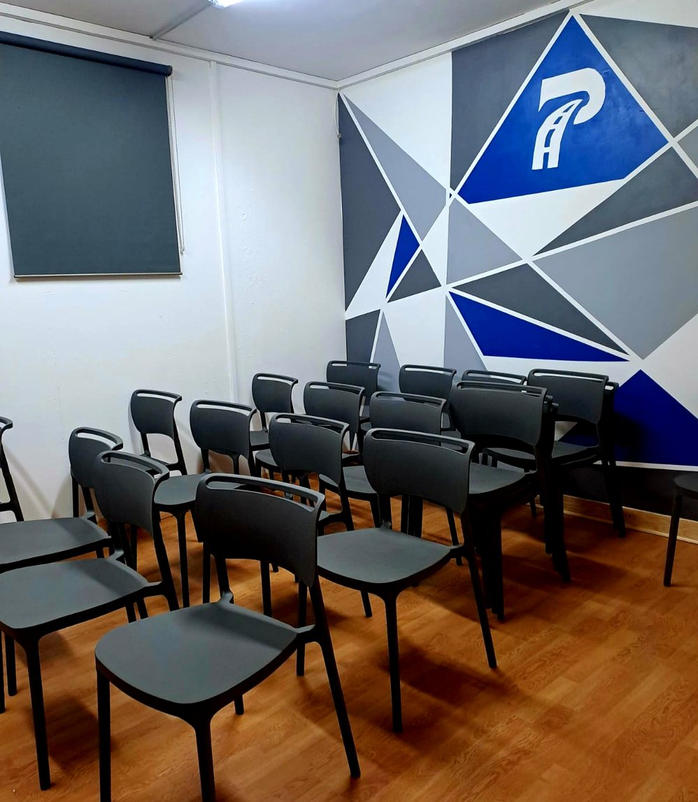 Salle de code avec ses chaises et la fresque bleue au logo Pilote Académie